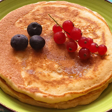 Hot Cakes Pancakes von Pronto auf Teller mit Blaubeeren und Johannisbeeren