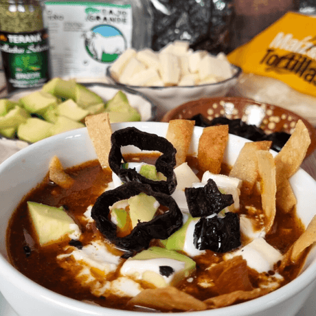 Tortilla Suppe aus Mexiko mit Avocado Queso und Chili im Hintergrund